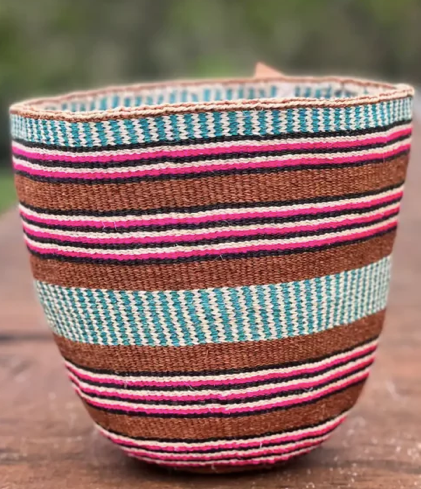 Woven basket with multicolored stripes on a wooden surface. the basket is about 7cm tall.